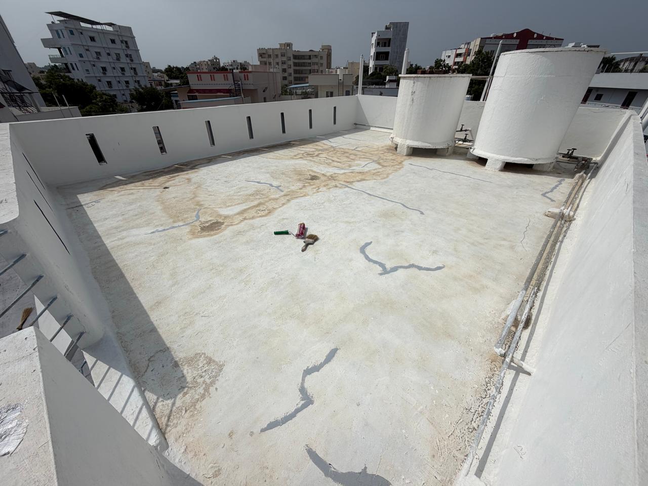 Weathered white terrace with sealed cracks and water stains before recoating in Warangal